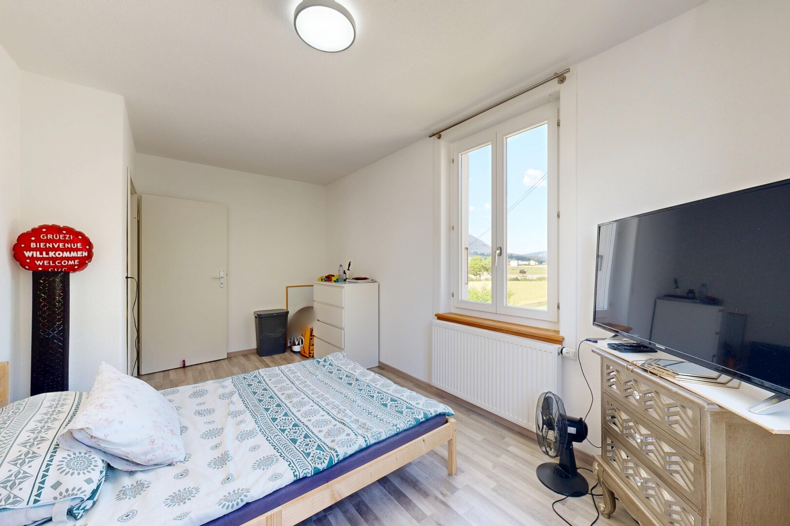 chambre avec radiateur, sol en finition bois, wood finish floor, inside property, et télévision