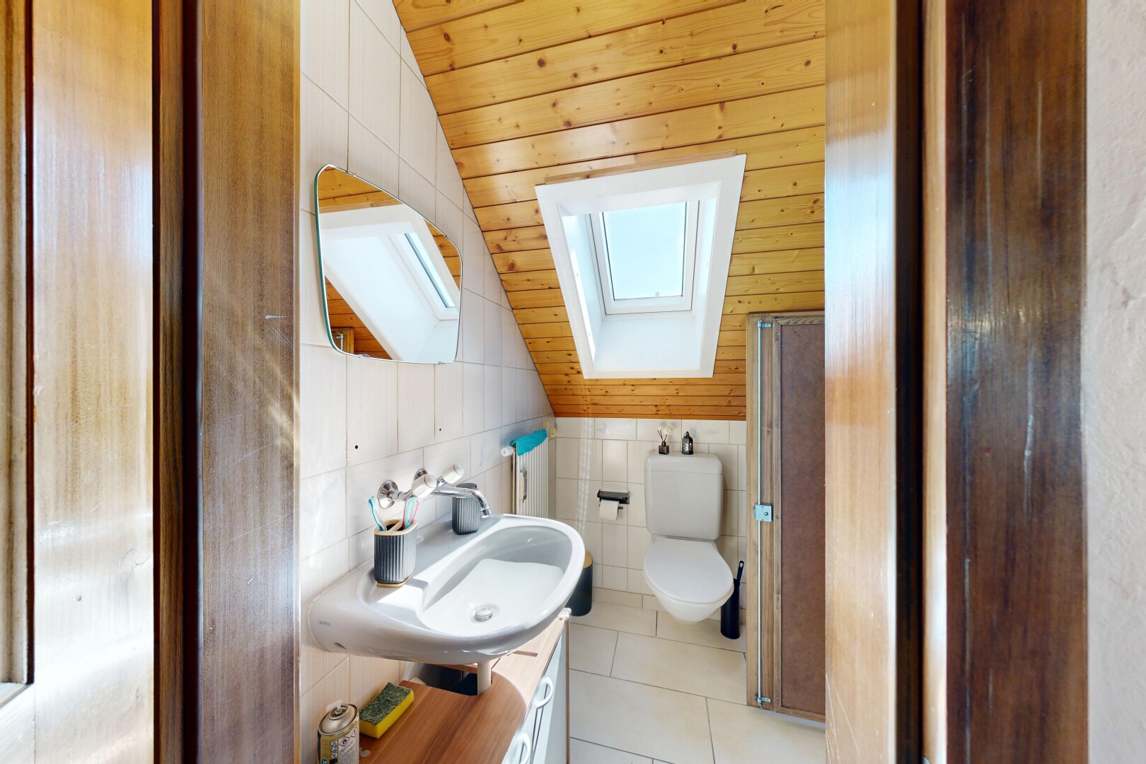 salle de bains avec plafond voûté, vaulted ceiling, miroir, inside property, et évier