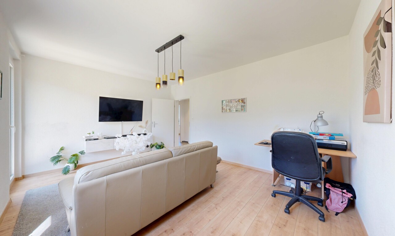 salon avec espace bureau, sol en finition bois, wood finish floor, télévision, et cloison sèche