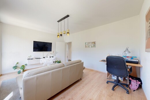 salon avec espace bureau, sol en finition bois, wood finish floor, télévision, et cloison sèche