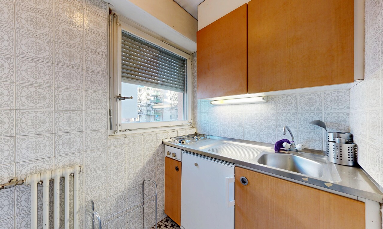 kitchen with stainless steel countertops, brown cabinetry, dishwasher, and radiator heating unit