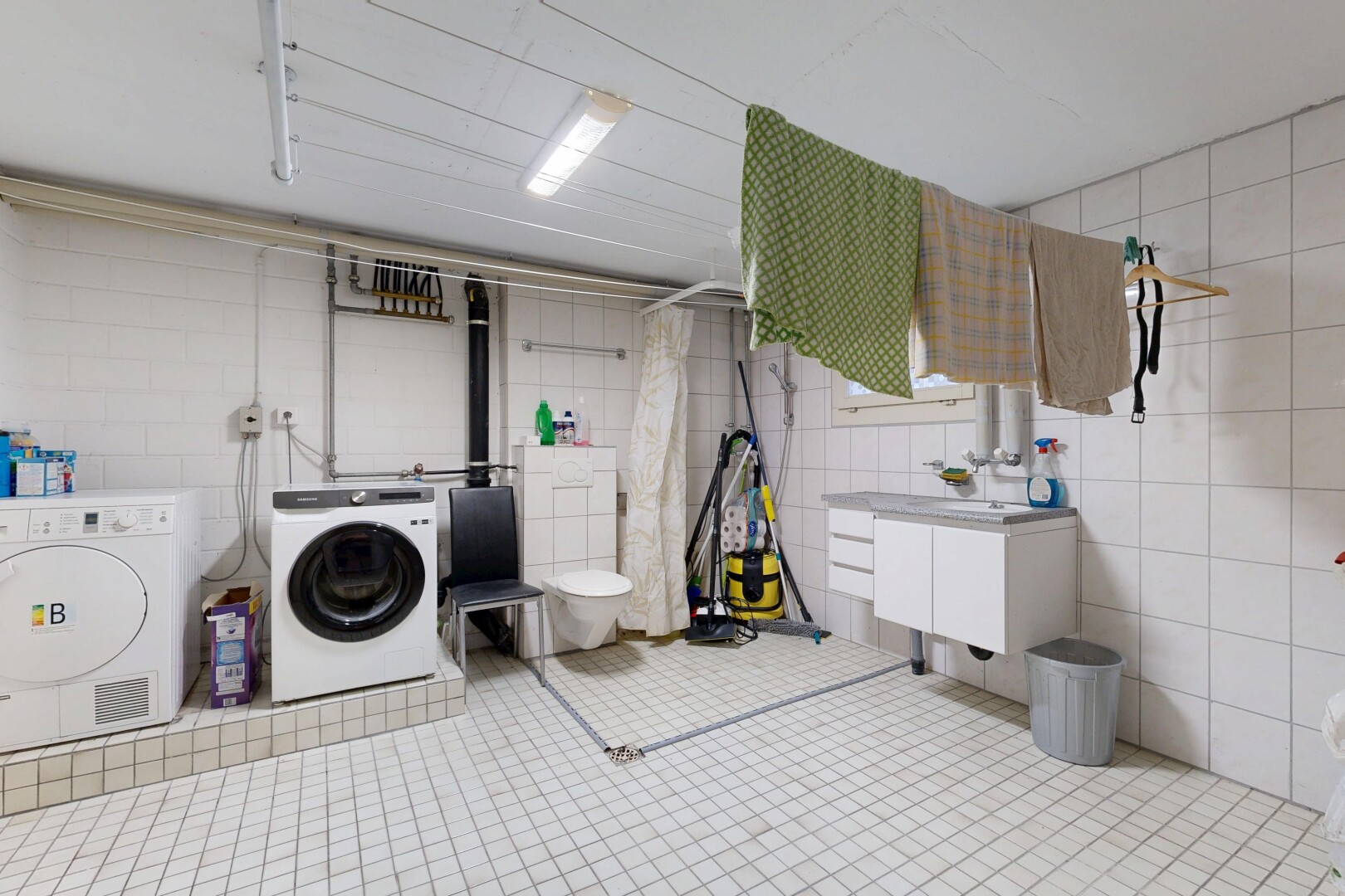 buanderie avec inside property, buanderie, mur en carrelage, tile wall, et lave-linge et sèche-linge séparés