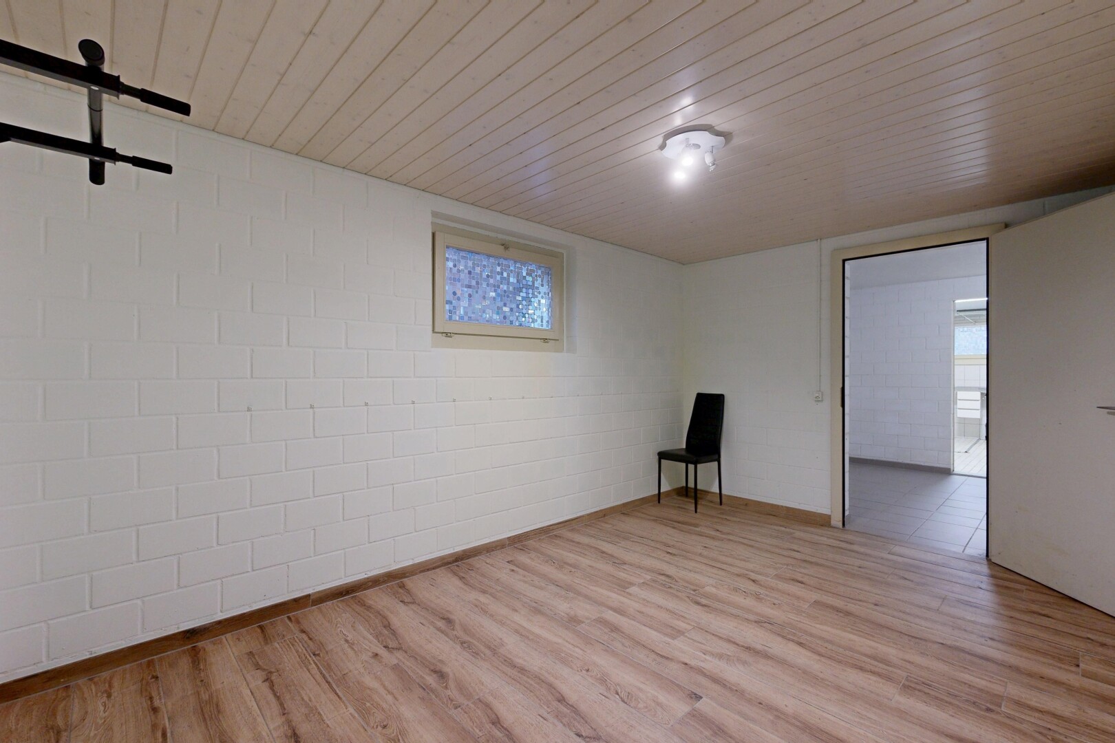 pièce vide avec plafond bas, low ceiling, mur en blocs de béton, concrete block wall, et sol en finition bois