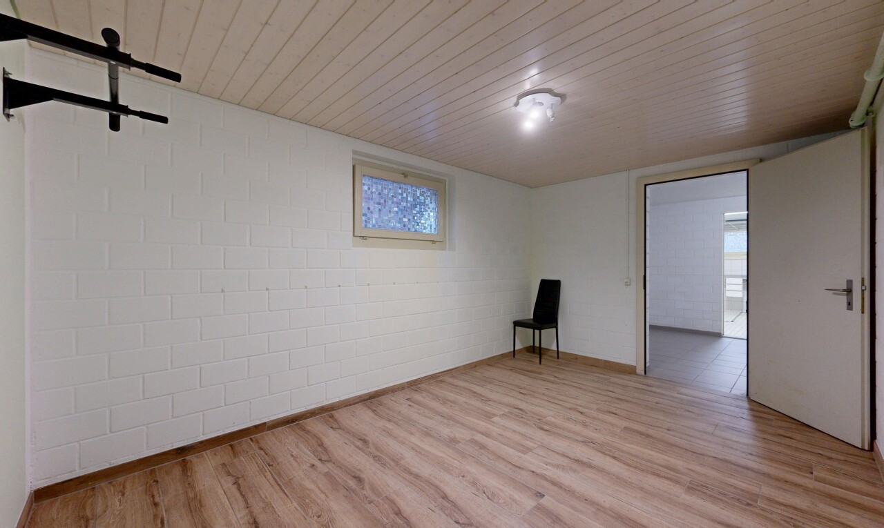 pièce vide avec plafond bas, low ceiling, mur en blocs de béton, concrete block wall, et sol en finition bois