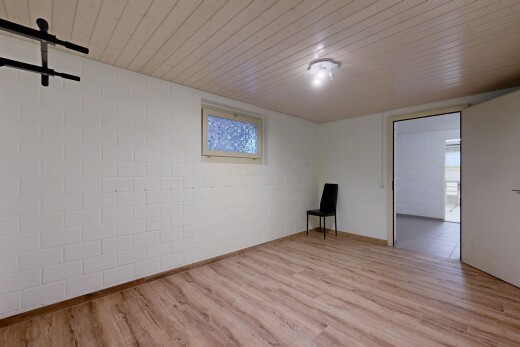 pièce vide avec plafond bas, low ceiling, mur en blocs de béton, concrete block wall, et sol en finition bois