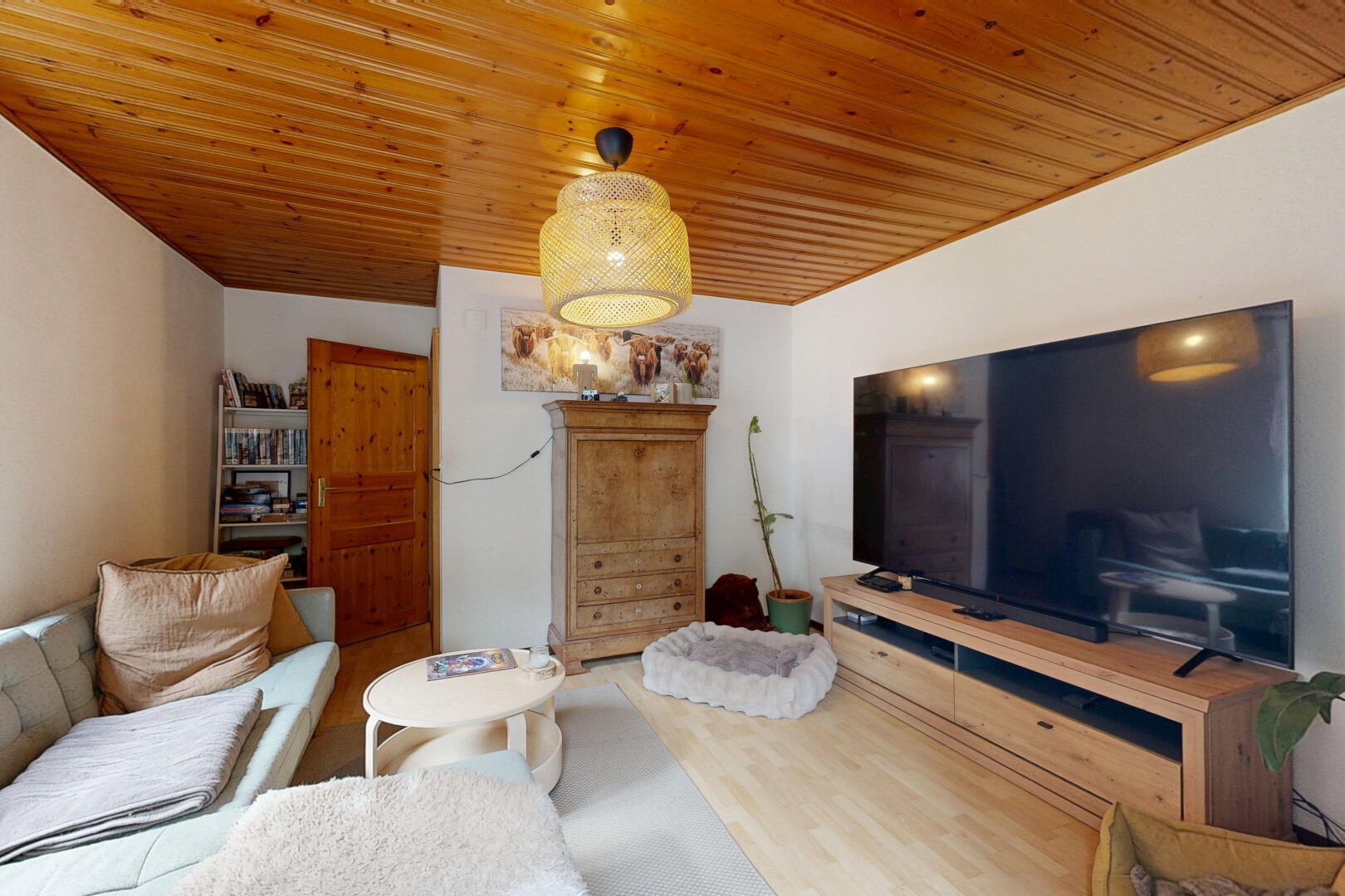 salon avec télévision, drywall, cloison sèche, wood finish floor, et sol en finition bois