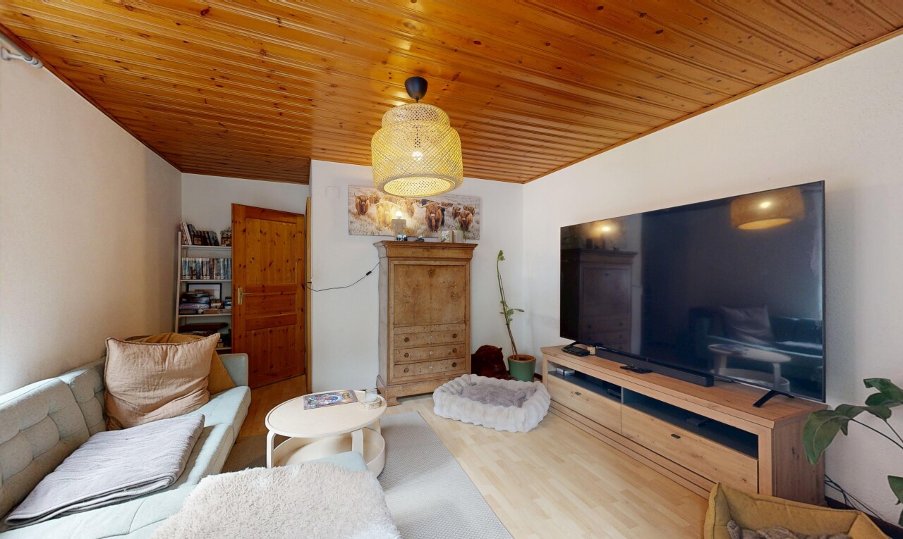 salon avec télévision, drywall, cloison sèche, wood finish floor, et sol en finition bois