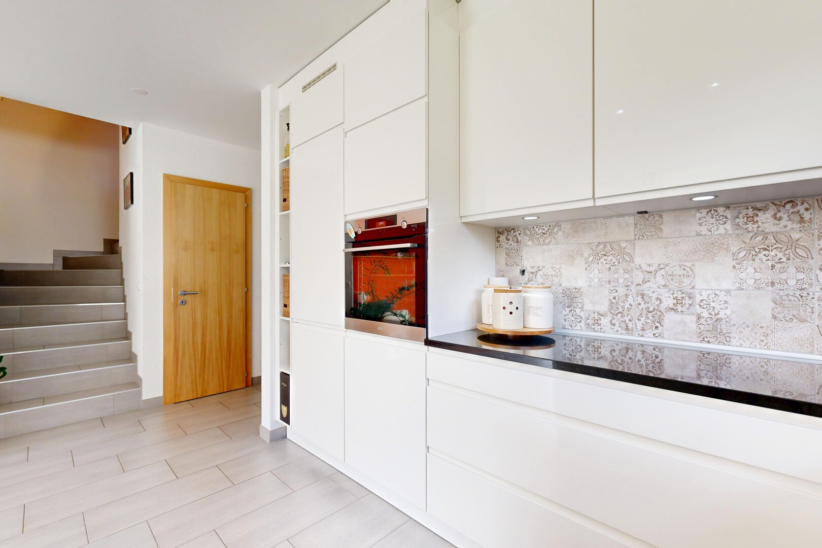küche mit weiße schränke, schränke mit flachen paneelen, ofen, inside property, und küchenrückwand beim herd