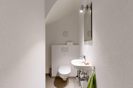 bathroom featuring a textured wall, light tile patterned floors, and vaulted ceiling