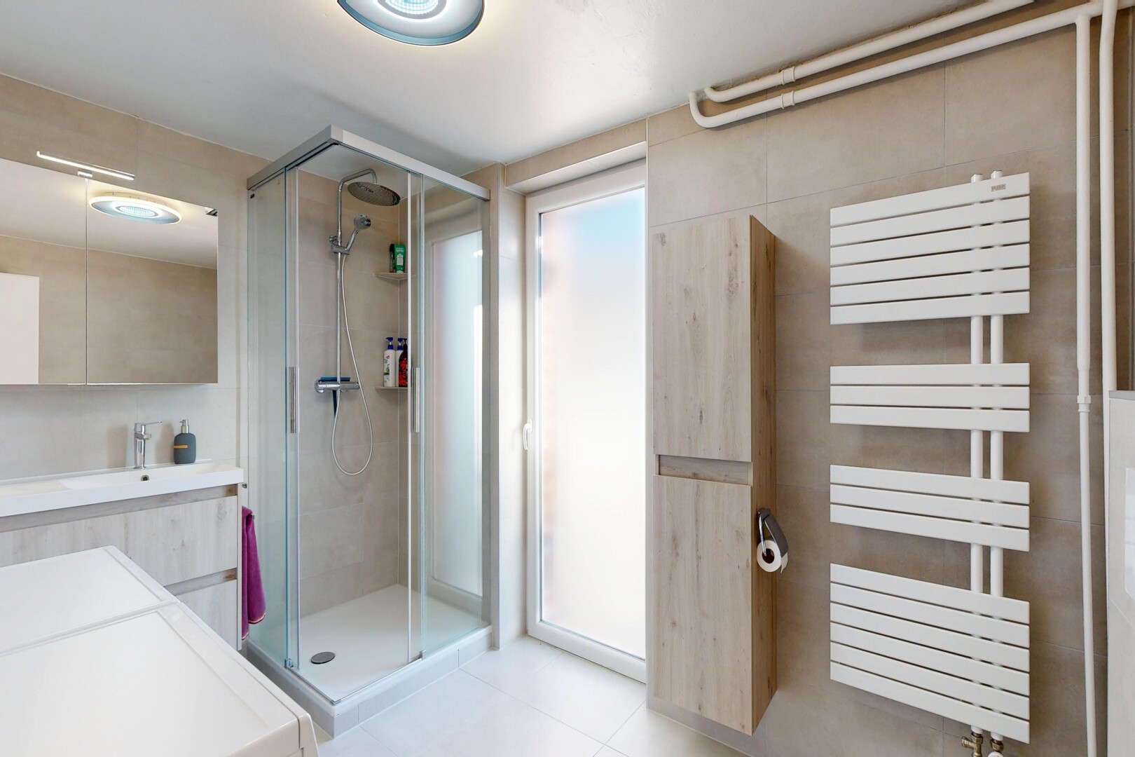 full bath with a stall shower, vanity, and a towel warming rack