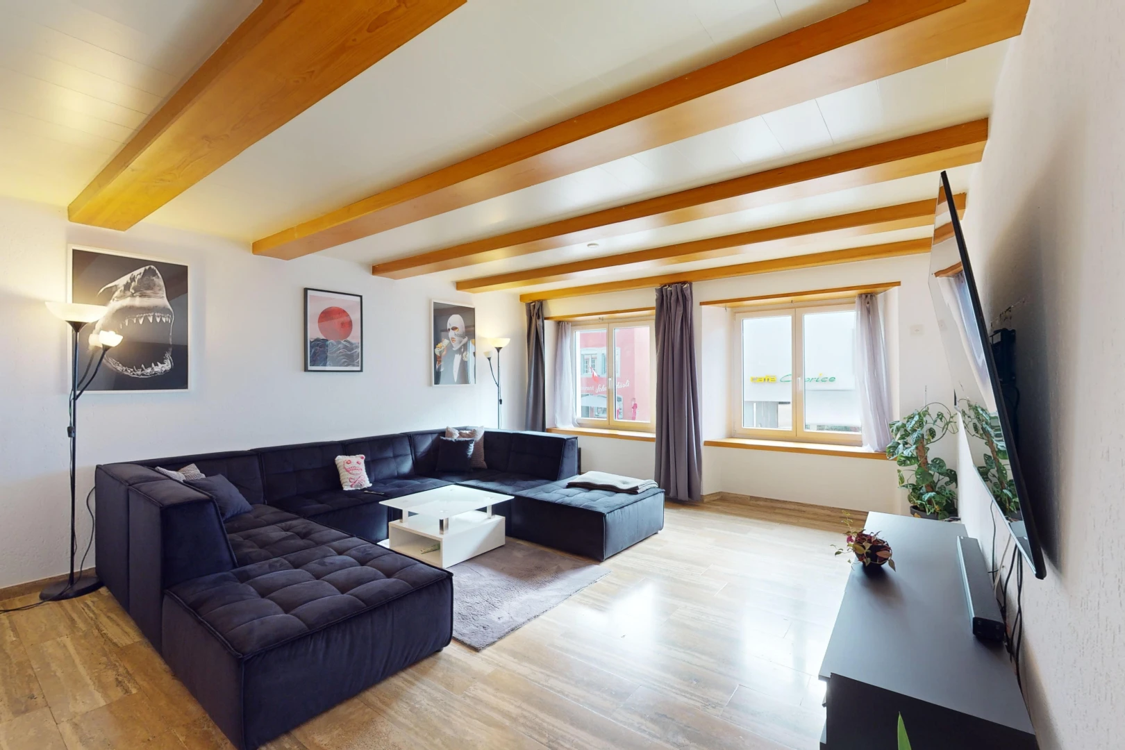 salon avec lumière naturelle, plancher de bois, et poutres apparentes