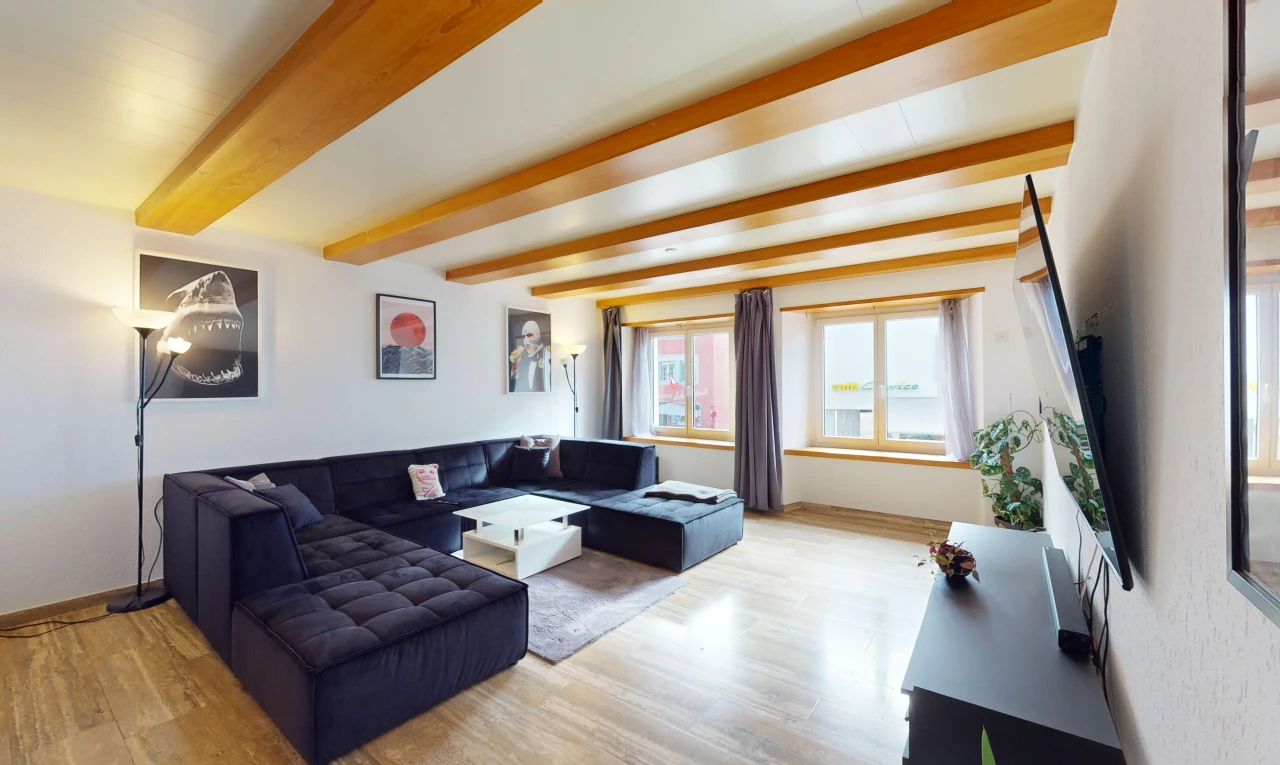 salon avec lumière naturelle, plancher de bois, et poutres apparentes