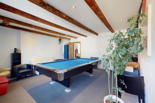 zimmer / schlafzimmer mit billard, balkendecke, und teppich