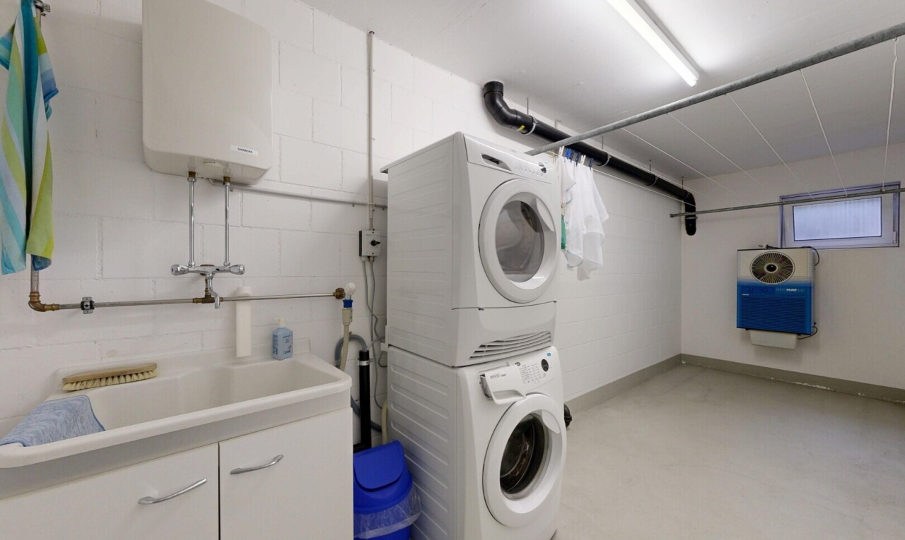 wäschekammer mit wasserkocher, waschturm, waschbecken, inside property, und betonboden