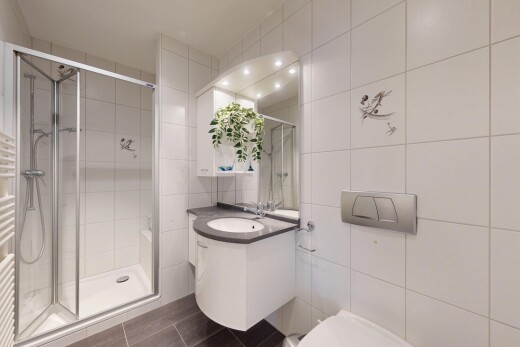 bathroom featuring tile walls, a towel warmer, vanity, a shower stall, and dark tile patterned flooring