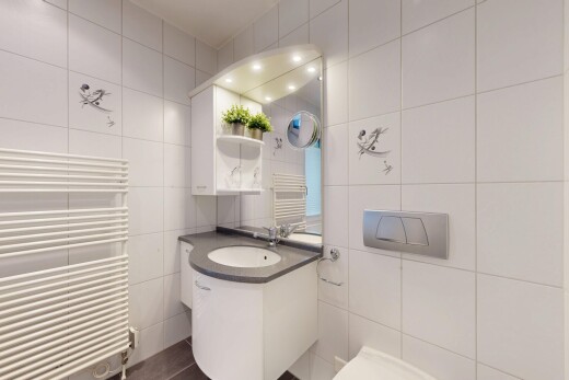 bathroom with a towel warming rack, radiator heating unit, tile walls, and vanity