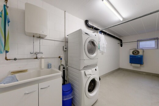 buanderie avec chauffe-eau, lave-linge et sèche-linge superposés, évier, inside property, et sol en béton