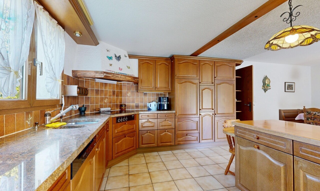 kitchen featuring decorative backsplash, light stone counters, light tile patterned flooring, wood finish cabinets, and pendant lighting
