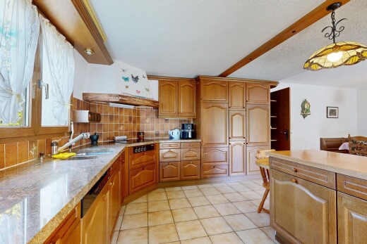kitchen featuring decorative backsplash, light stone counters, light tile patterned flooring, wood finish cabinets, and pendant lighting