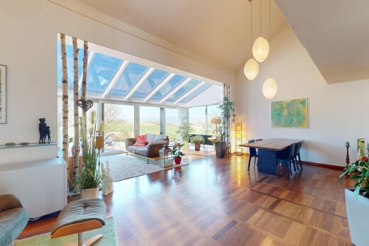 salon / salle à manger avec cloison sèche, plinthes murales, lumière naturelle, plafond voûté, et plafond haut
