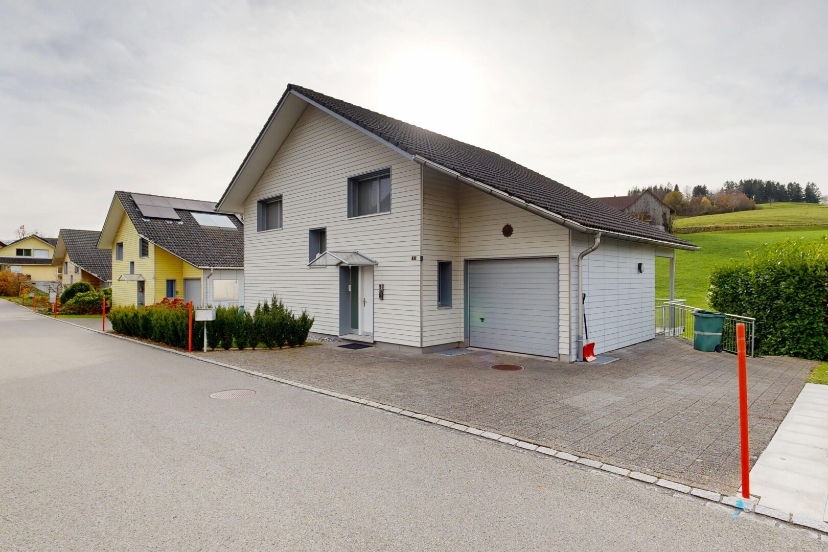 façade avec bardage horizontal, property visible, garage attaché, allée, et overcast