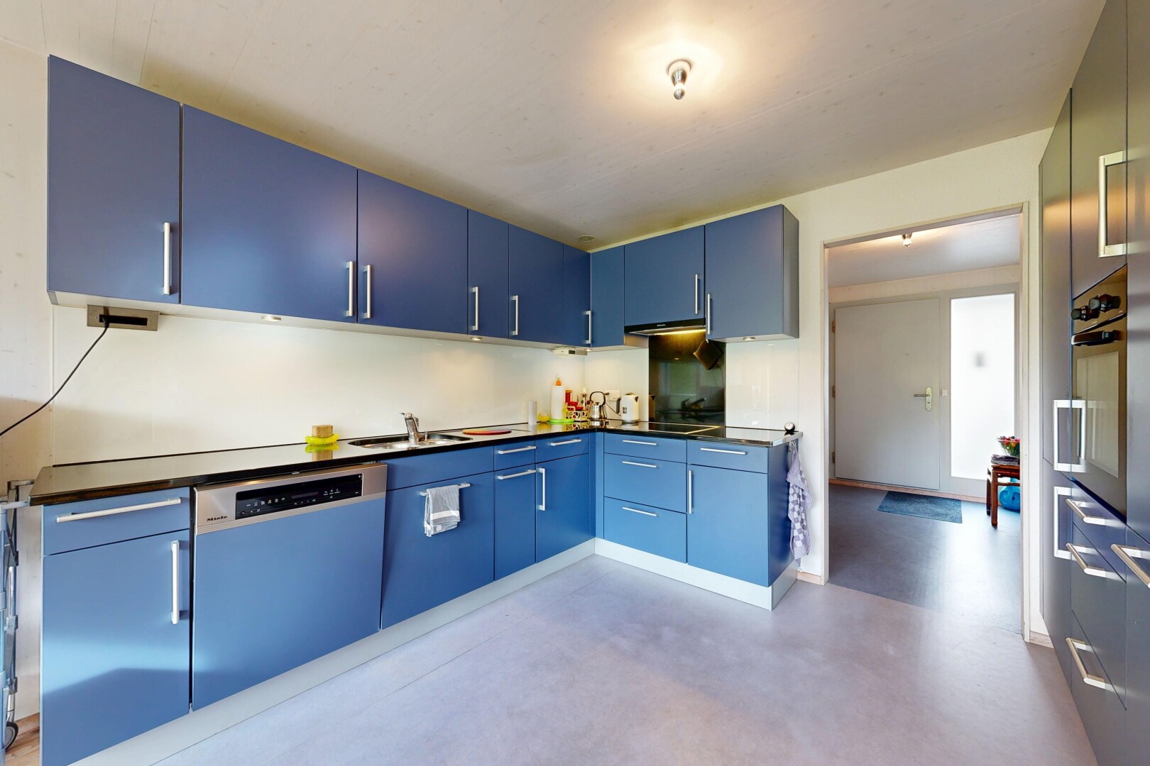 cuisine avec armoires bleues, plans de travail, sol en béton, concrete floor, et inside property