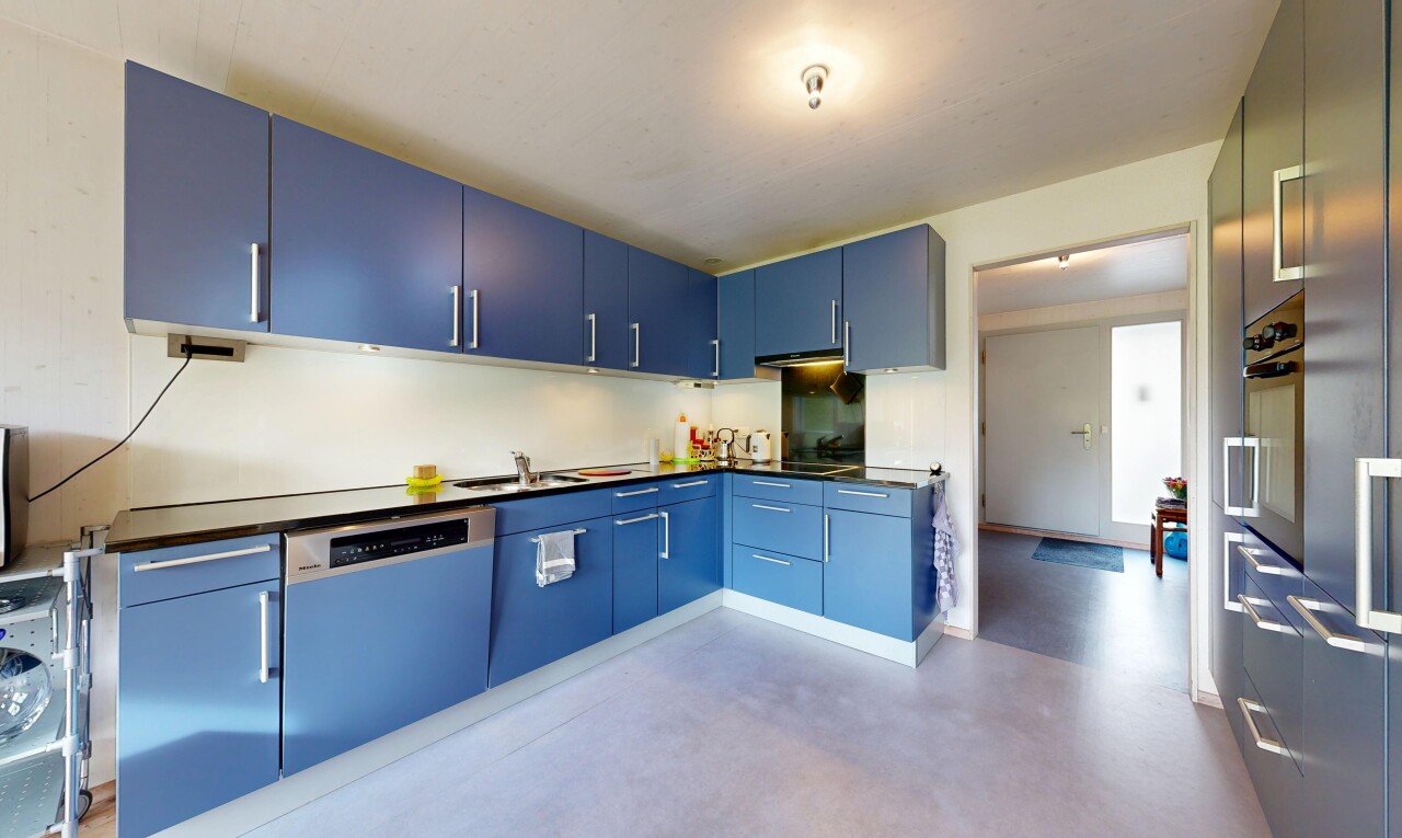 cuisine avec armoires bleues, plans de travail, sol en béton, concrete floor, et inside property