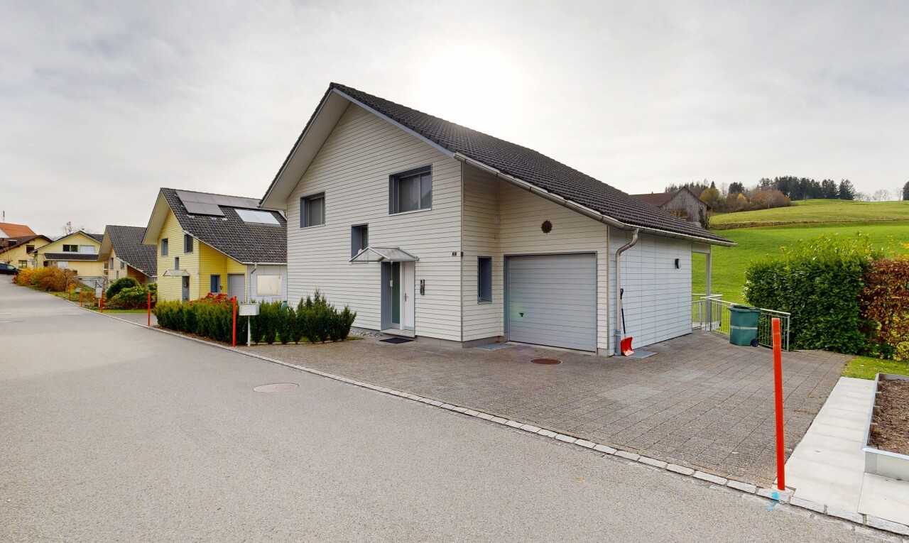 façade avec bardage horizontal, property visible, garage attaché, allée, et overcast