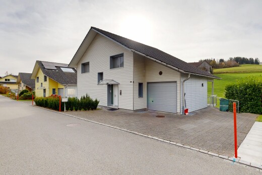 façade avec bardage horizontal, property visible, garage attaché, allée, et overcast