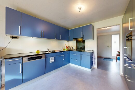cuisine avec armoires bleues, plans de travail, sol en béton, concrete floor, et inside property