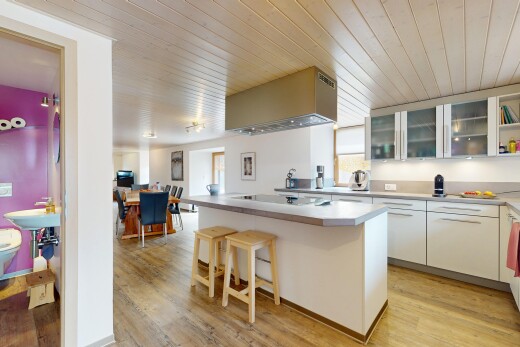 cuisine avec armoires avec insert en verre, bar de cuisine, sol en finition bois, wood finish floor, et plans de travail