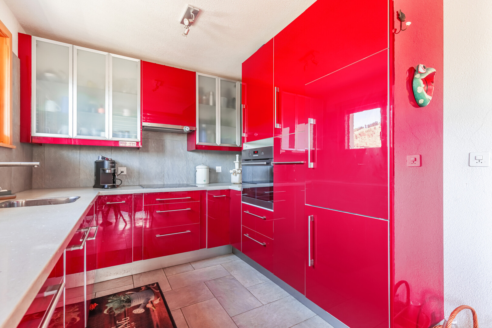 cuisine avec armoires rouges, red cabinets, light floor, four, et évier