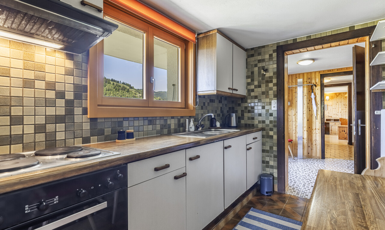 cuisine avec four, dark floor, hotte, white cabinets, et armoires blanches