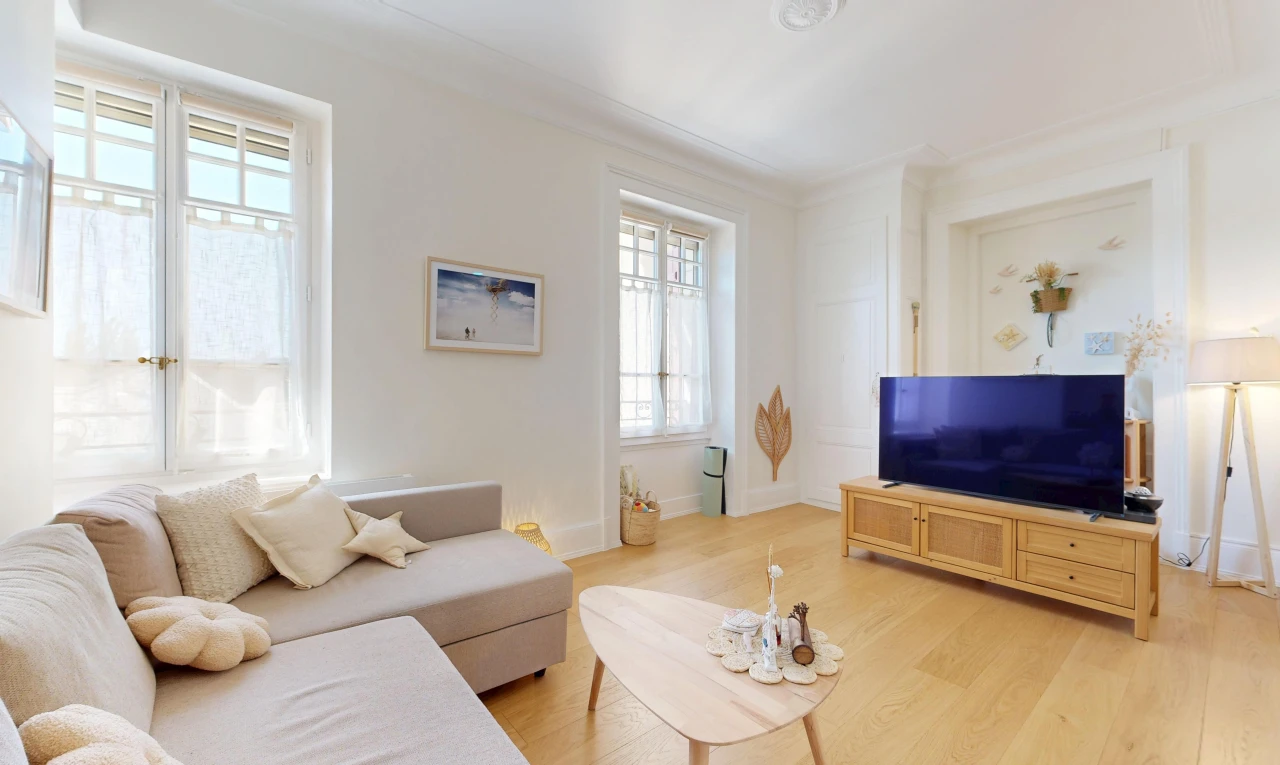 salon avec télévision, lumière naturelle, wood finish floor, sol en finition bois, et drywall