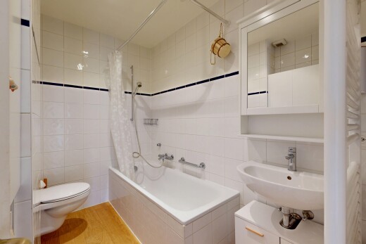 full bath featuring tile walls, tiled shower / bath, and light wood-style flooring