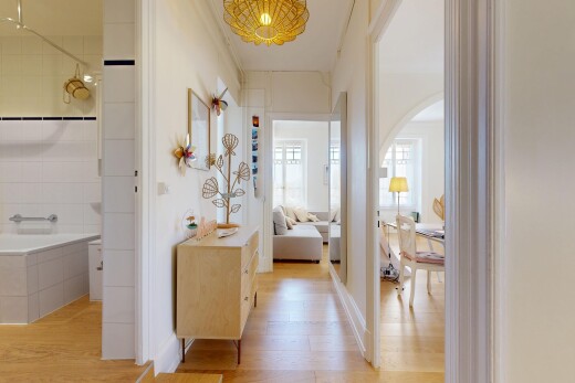 hall featuring light wood-style flooring, decorative light fixtures, and arched walkways