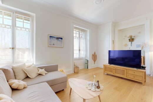 salon avec télévision, lumière naturelle, wood finish floor, sol en finition bois, et drywall