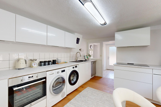 küche mit waschbecken, arbeitsplatten, parkettboden, ofen, und weiße schränke