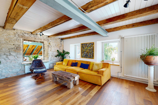 wohnzimmer mit steinwand, natürliches licht, kühler, balkendecke, und parkettboden