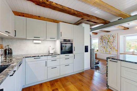 küche mit schranktüren mit vertiefter mittelplatte, balkendecke, parkettboden, ofen, und natürliches licht