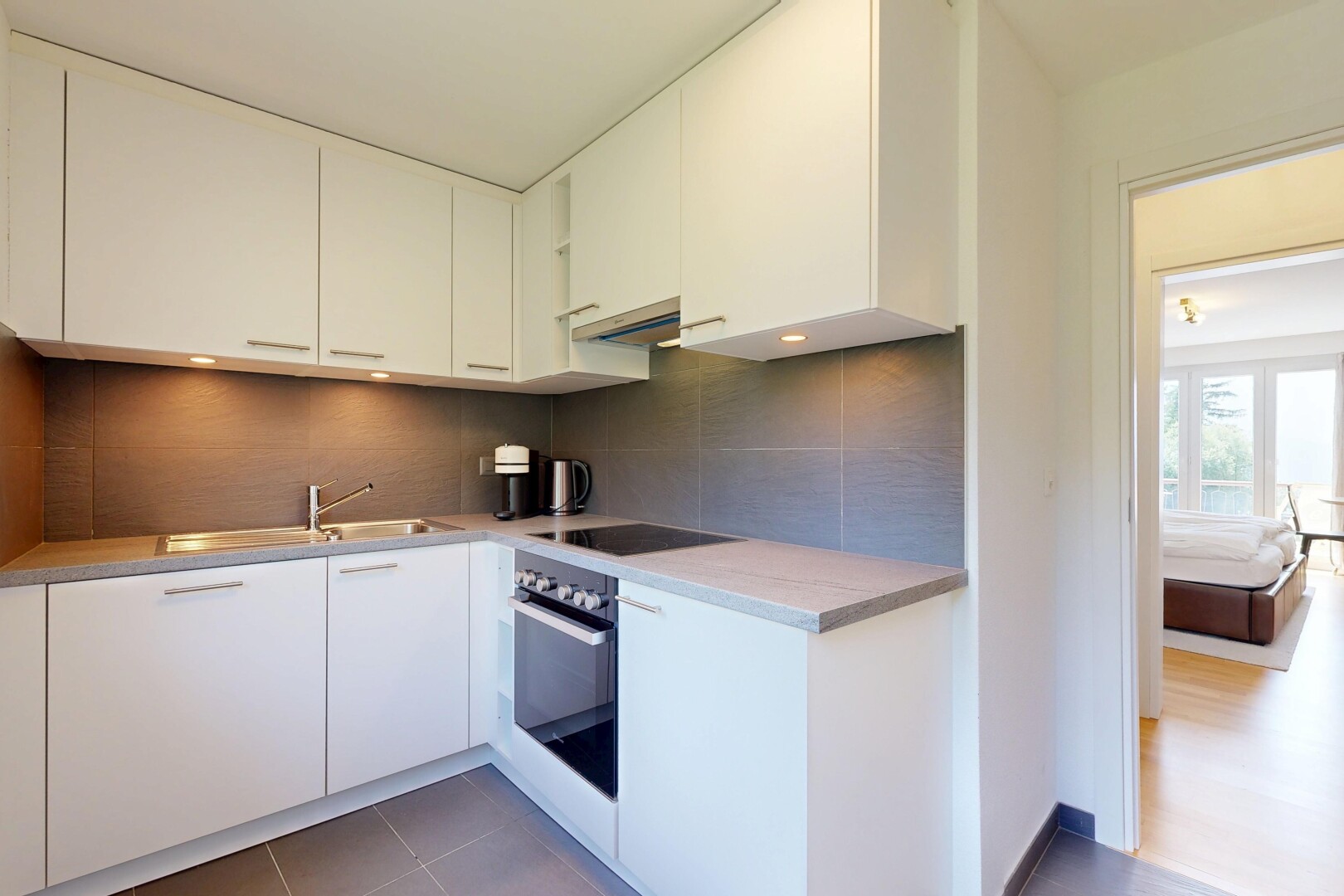 cuisine avec backsplash, dosseret, armoires blanches, four, et natural light