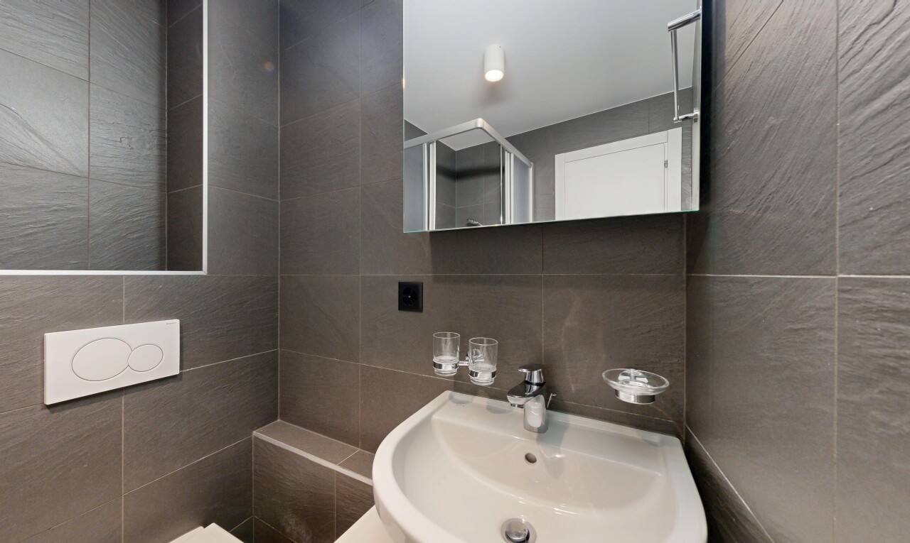 salle de bains avec tile wall, mur en carrelage, miroir, évier, et inside property