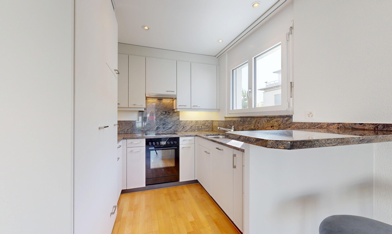 küche mit two heights countertops, ofen, light floor, dark countertops, und white cabinets