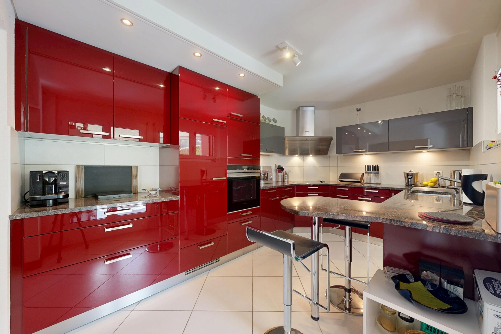 kitchen featuring red cabinets, oven, tasteful backsplash, modern cabinets, and a kitchen breakfast bar