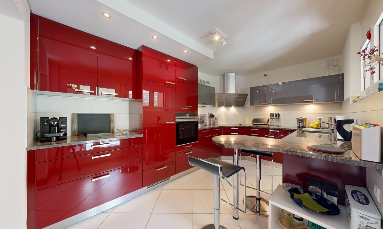 kitchen featuring red cabinets, oven, tasteful backsplash, modern cabinets, and a kitchen breakfast bar