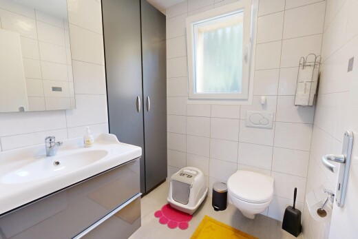 salle de bains avec mur en carrelage, tile wall, lavabo (ou coiffeuse selon le contexte), miroir, et lumière naturelle