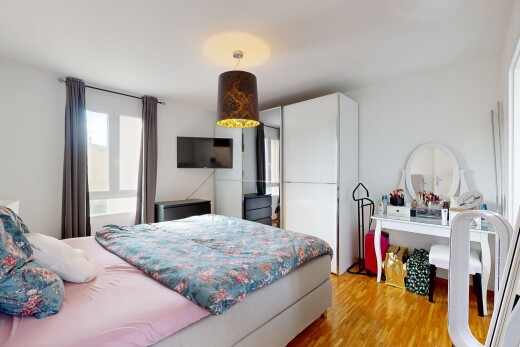 chambre avec sol en finition bois, wood finish floor, télévision, inside property, et lumière naturelle