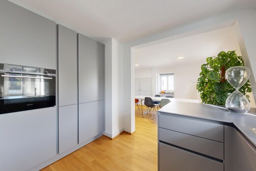 kitchen with gray cabinets, black oven, light wood-style floors, and light countertops
