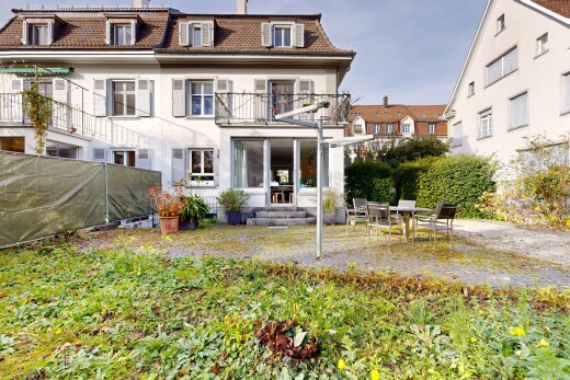 view of property with mansard roof, a balcony, a patio area, and stucco siding