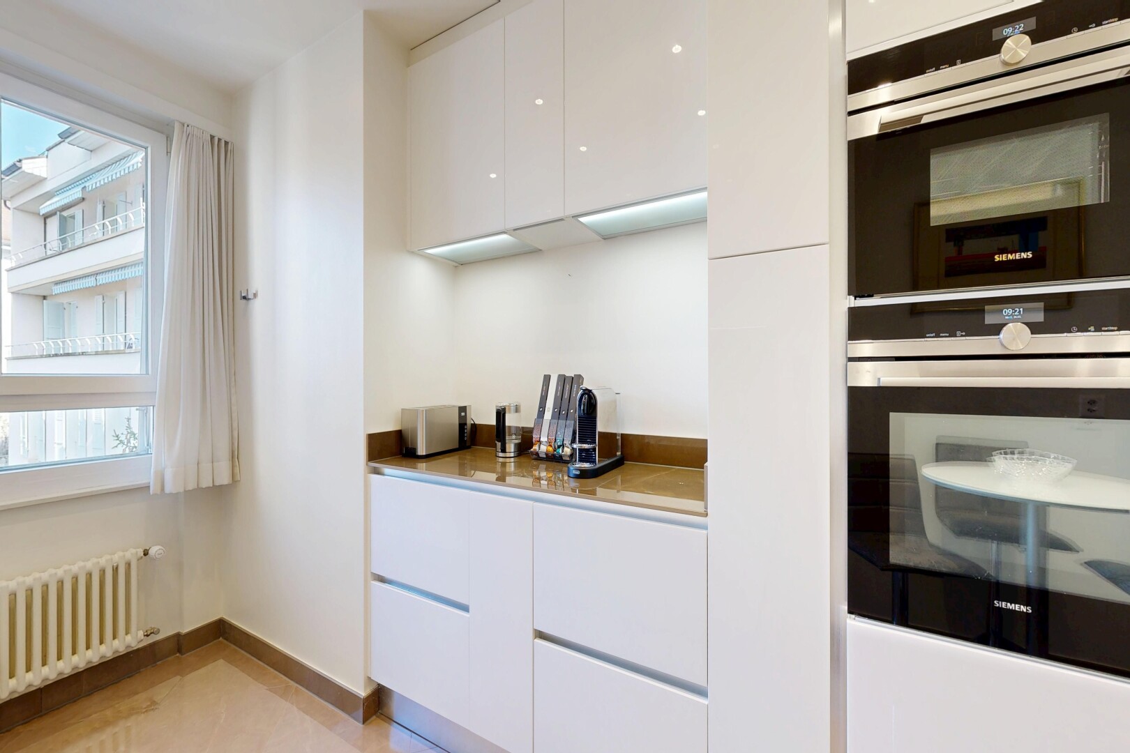 kitchen with modern cabinets, double oven, white cabinetry, and radiator heating unit